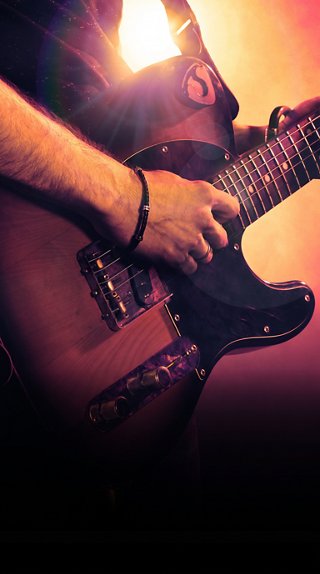 Musician holding an electric guitar on stage with warm lighting | MSC Cruises