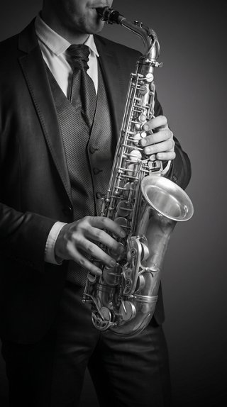 A person in an elegant suit holds a saxophone, evoking a mood of jazz and style | MSC Cruises