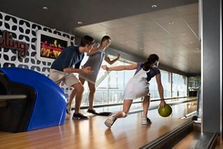 A family enjoys bowling together in a modern entertainment area on a cruise ship | MSC Cruises