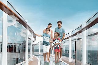 Una familia camina sobre el puente de cristal en un crucero bajo el cielo azul | MSC Cruises