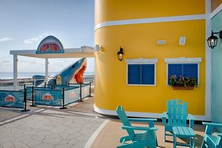Colorful seating and tables in the outdoor area of MSC World America next to the sea | MSC Cruises