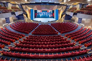Spacious theater with rows of red seats and a large stage for onboard entertainment | MSC Cruises