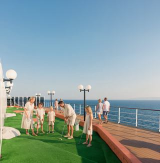 Families enjoying mini golf on the open deck with a stunning view of the sea | MSC Cruises