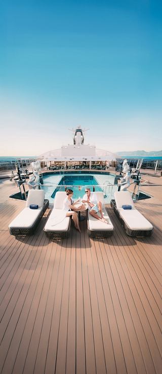 Elegant pool area with sun loungers and clear blue sky on a cruise ship deck | MSC Cruises