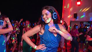 A woman dances with wireless headphones among colorful lights and guests at MSC Cruises Silent Disco | MSC Cruises