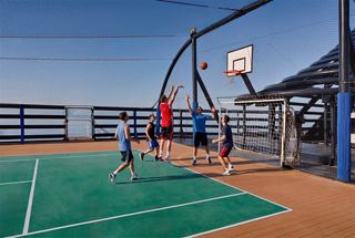 A group plays basketball on a sports court with panoramic sea views | MSC Cruises