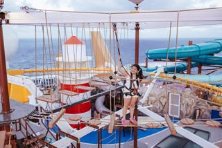 A child navigates the ropes bridge at The Harbour on MSC World America with the sea visible | MSC Cruises