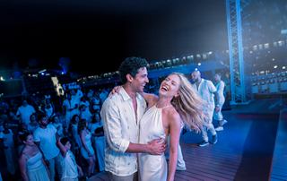 Guests enjoy a lively themed party together on the open deck at night | MSC Cruises