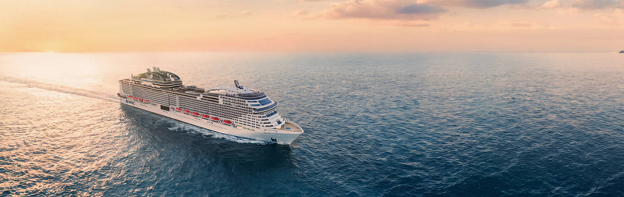 Cruise ship sailing on calm sea with sunset and open sky above | MSC Cruises