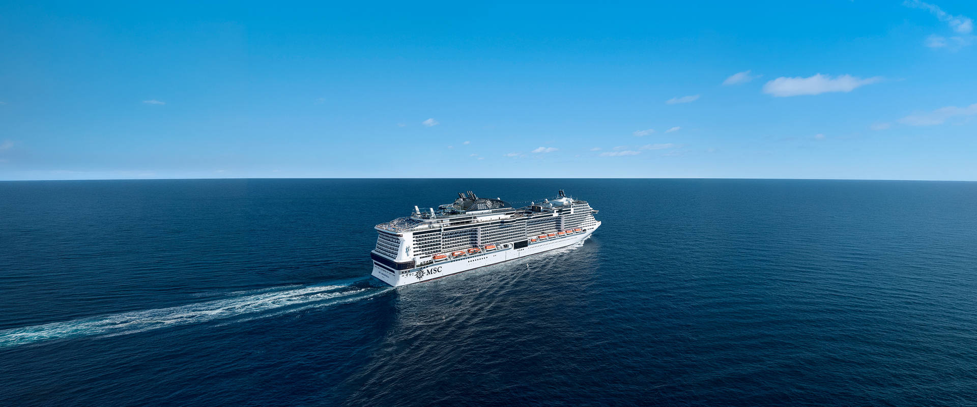 Cruise ship sails across calm blue sea beneath a clear sky | MSC Cruises