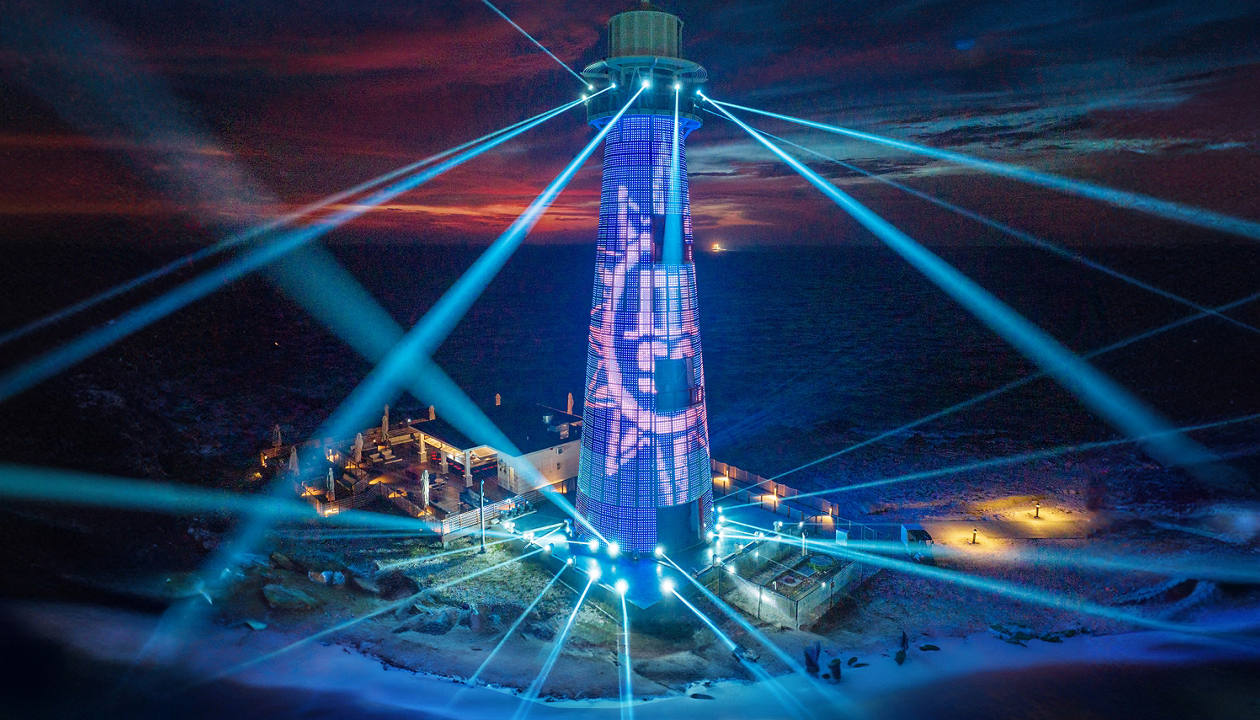 Ocean Cay lighthouse illuminated by vibrant beams in a dazzling night light show | MSC Cruises