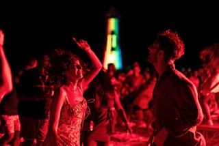 Guests dance together at a vibrant party with colorful lights near the ocean | MSC Cruises