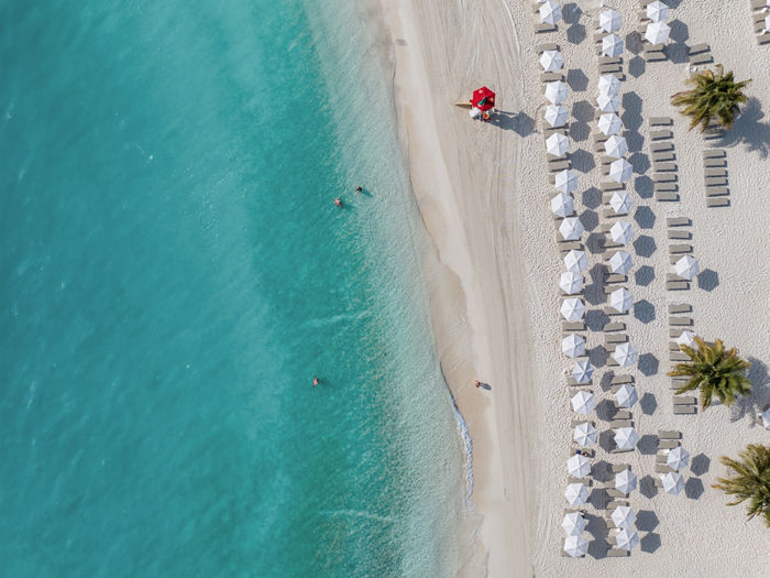 Turquoise sea beside a white sandy beach lined with umbrellas and loungers | MSC Cruises