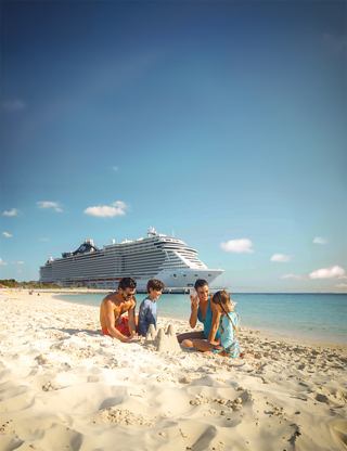 Children build a sandcastle on a sunny beach with a scenic island in the distance | MSC Cruises