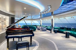 Piano and comfortable sitting area with sea views in the Top Sail Lounge on MSC Poesia | MSC Cruises