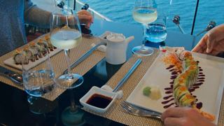A couple enjoys sushi and wine with a view of the sea through a glass wall | MSC Cruises