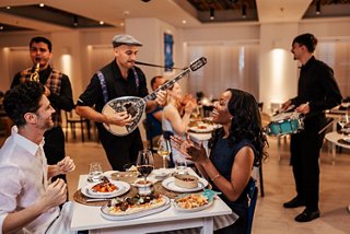 Guests enjoy dinner accompanied by live music in a Greek restaurant setting | MSC Cruises