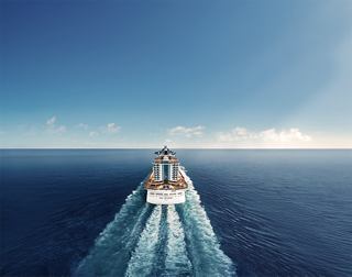 A cruise ship travels across a vast blue sea under a clear sky, leaving a gentle wake | MSC Cruises