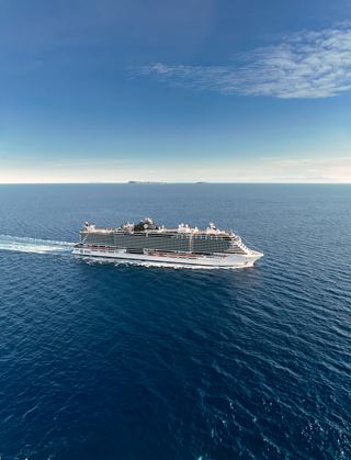 Cruise ship sails across a blue ocean beneath a clear sky | MSC Cruises