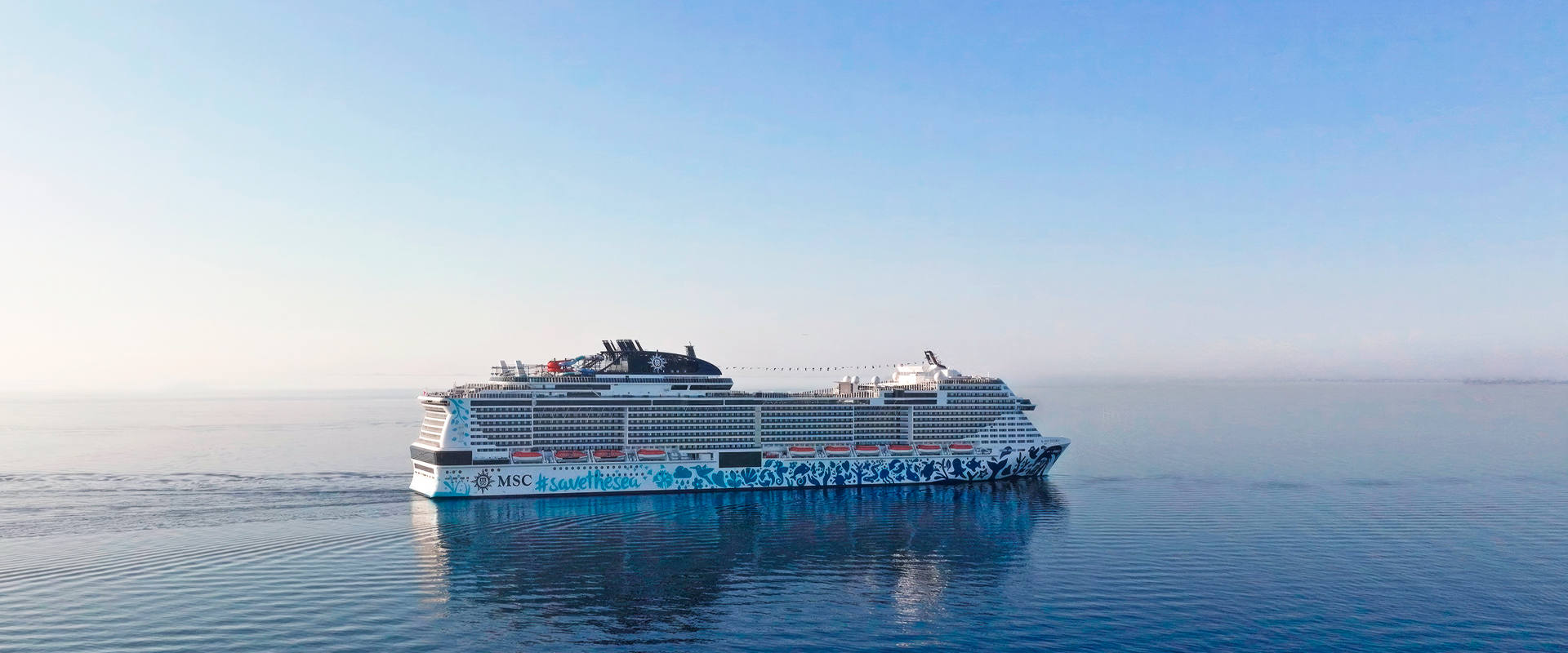 A cruise ship sails on calm blue water beneath a clear sky | MSC Cruises