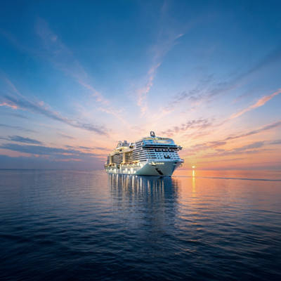 MSC Grandiosa cruise ship sails across calm waters at sunset | MSC Cruises