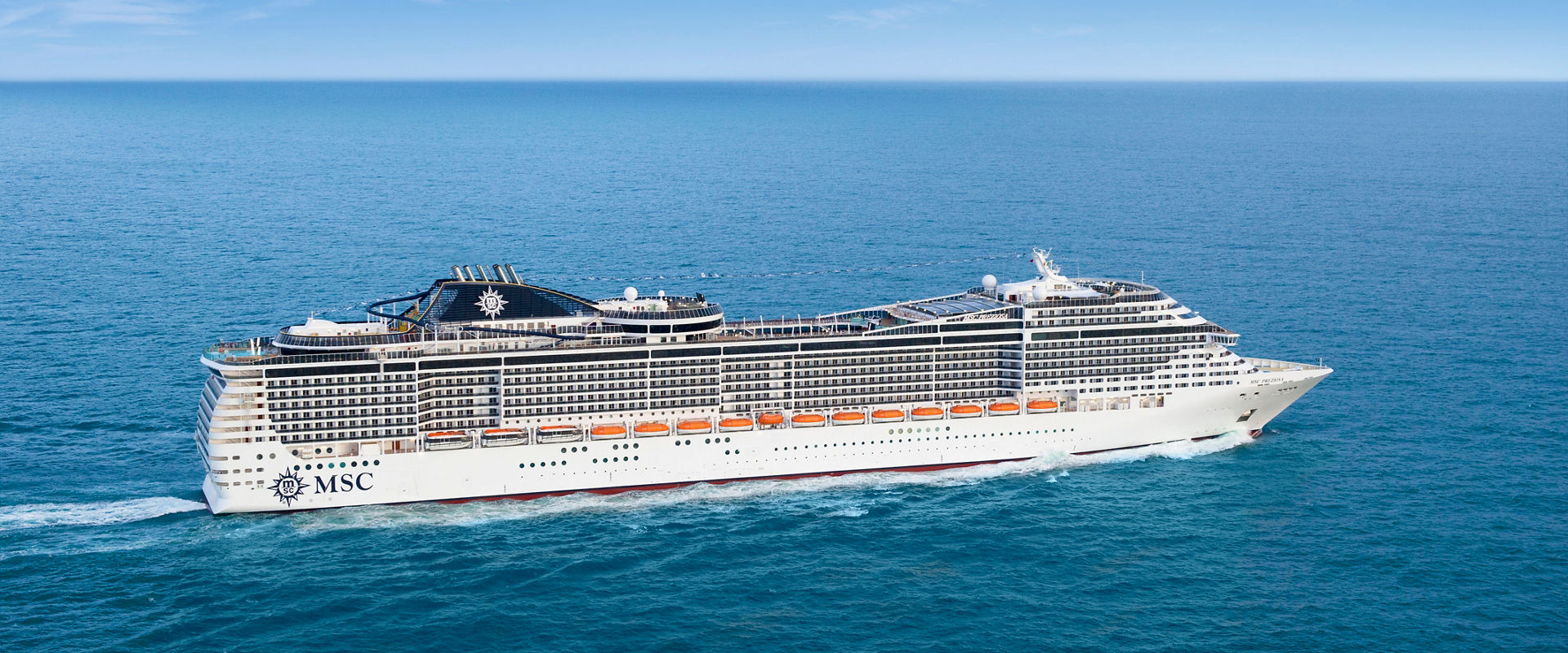 MSC Preziosa sails across the tranquil sea beneath a clear blue sky | MSC Cruises