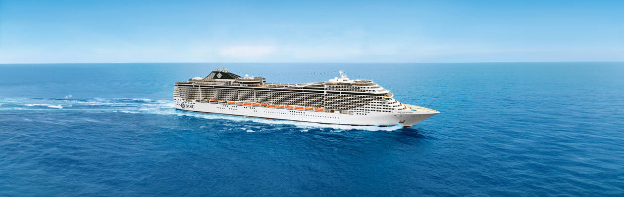 A cruise ship travels across calm blue waters beneath a clear sky | MSC Cruises