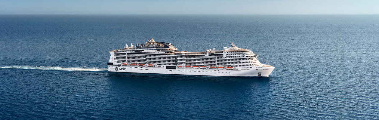 Cruise ship sails across a tranquil blue sea beneath a clear sky | MSC Cruises