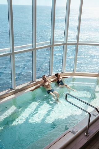 Two people enjoy an infinity pool with ocean views through expansive windows | MSC Cruises