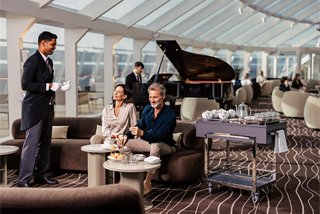 Guests enjoy a welcoming atmosphere with piano music and attentive service in a luxurious lounge | MSC Cruises