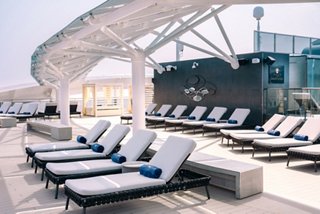 Sunbeds with blue and white towels on the sundeck beside the pool of a cruise ship | MSC Cruises