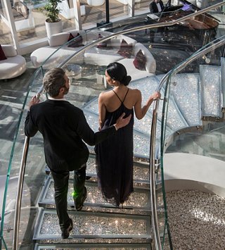 A couple walks down the staircase in the elegant MSC Yacht Club lounge area | MSC Cruises