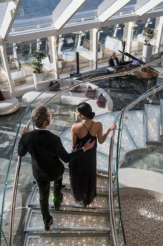 Guests walk down the staircase surrounded by elegant settings in MSC Yacht Club | MSC Cruises