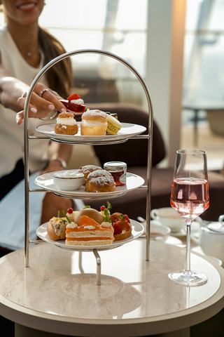 A woman serves pastries and drinks at a stylish table in the MSC Yacht Club lounge | MSC Cruises