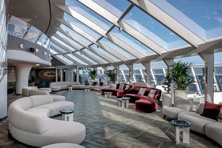 Spacious and bright lounge in MSC Yacht Club with sofas, glass walls and panoramic views | MSC Cruises