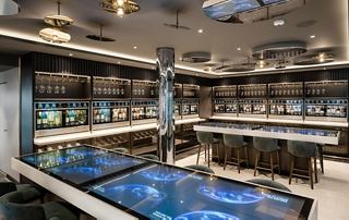 Eine moderne Weinbar mit elegantem Interieur und Regalen voller Flaschen | MSC Cruises