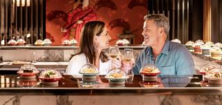 Two people enjoy sushi and drinks together in a welcoming onboard restaurant setting | MSC Cruises