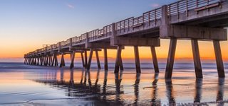 A pier extends over the water at sunset, creating a serene and welcoming ambiance | MSC Cruises