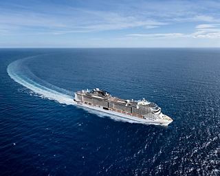 A magnificent cruise ship gliding through the tranquil blue ocean under a clear sky | MSC Cruises