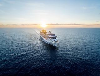 A cruise ship sails through calm waters while the sun rises on the horizon | MSC Cruises