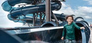 A boy in a green shirt stands by a water slide on a cruise ship deck | MSC Cruises