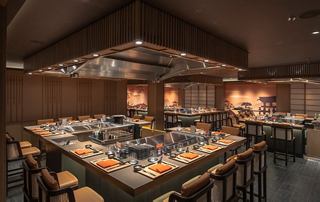 Ambiente moderno del ristorante con tavoli teppanyaki e illuminazione calda | MSC Crociere