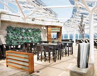 A stylish bar area in the MSC Yacht Club, featuring seating and a view of the ocean | MSC Cruises
