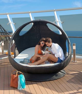 Una pareja disfrutando de un momento relajante juntos en una silla en forma de capullo en la cubierta del MSC Divina | MSC Cruceros