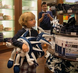 A child joyfully engages with colourful toys in a shop while an adult observes nearby | MSC Cruises