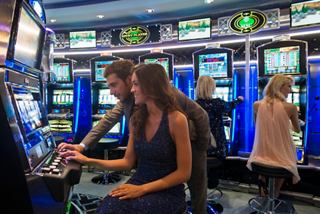 Friends enjoying the excitement of the Casino Veneziano aboard MSC Divina, surrounded by vibrant slot machines | MSC Cruises