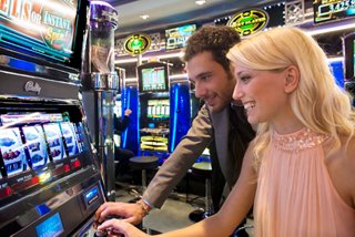 Deux amis profitent d'un moment amusant à une machine à sous dans le vibrant casino à bord de MSC Divina | MSC Cruises