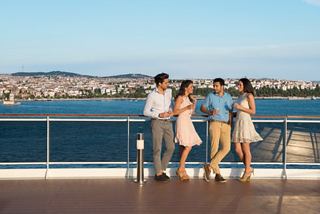 A group of friends enjoying each other's company on a deck with a scenic view of Turkey's coastline | MSC Cruises