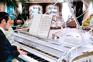 A talented musician plays a grand piano, creating a warm atmosphere for guests on board MSC Fantasia | MSC Cruises