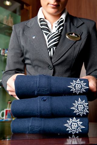 A crew member neatly arranges folded towels with the MSC logo, ready to assist guests in the onboard shop | MSC Cruises
